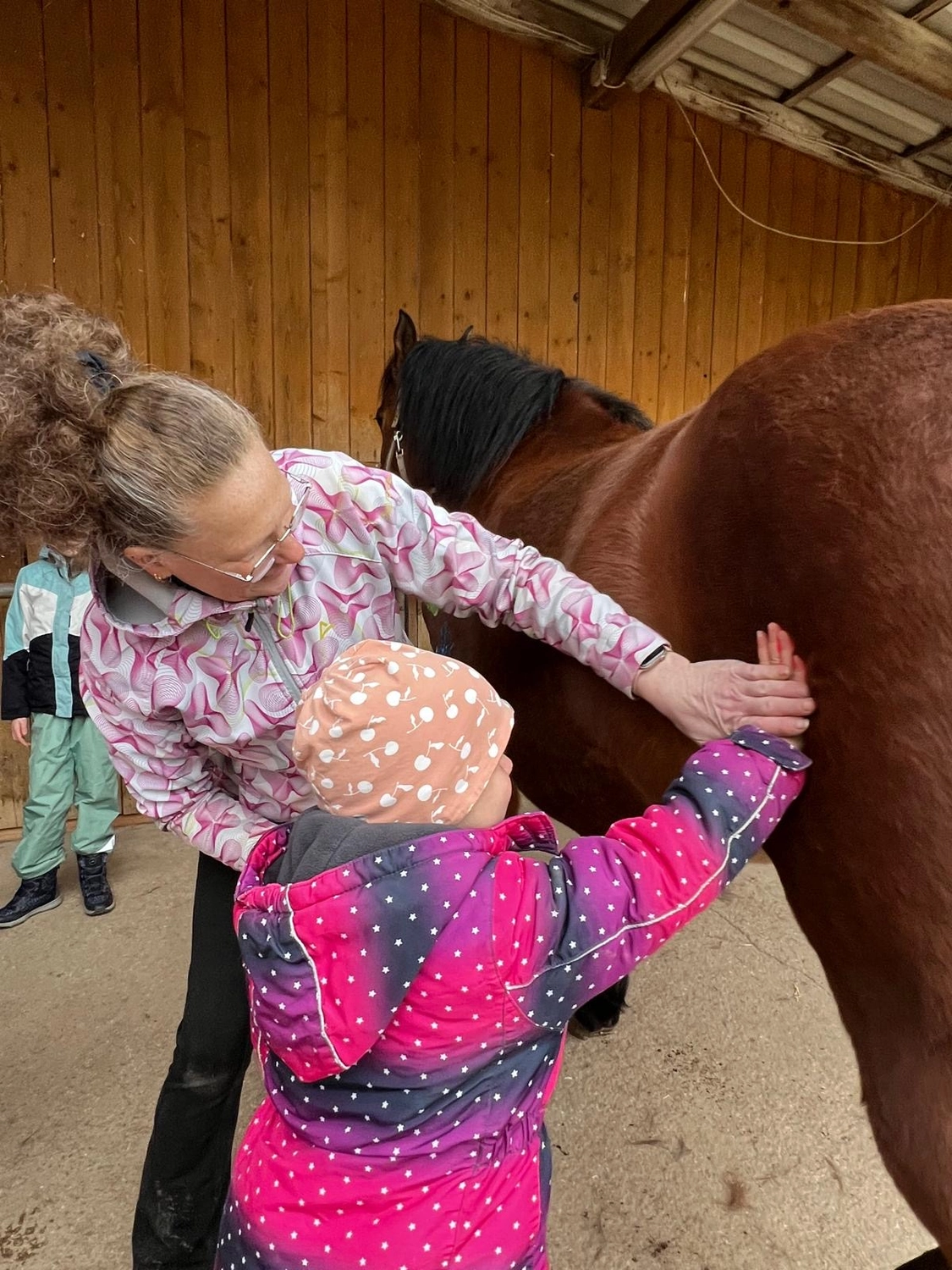 Seelenanker Pferde - Pferdetrainer und Reitpädagoge - Ein Erwachsener und ein Kind Pferdepflege ein braunes Pferd.